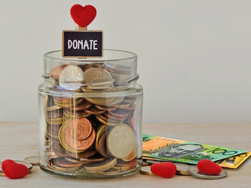 Money jar with coins inside and dollar notes on the side with red love hearts around it